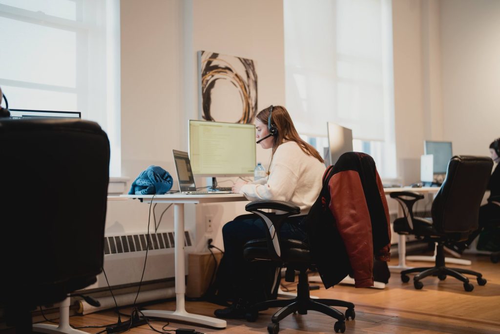 Four Eyes team member on a headset call at her desk in the bright open office