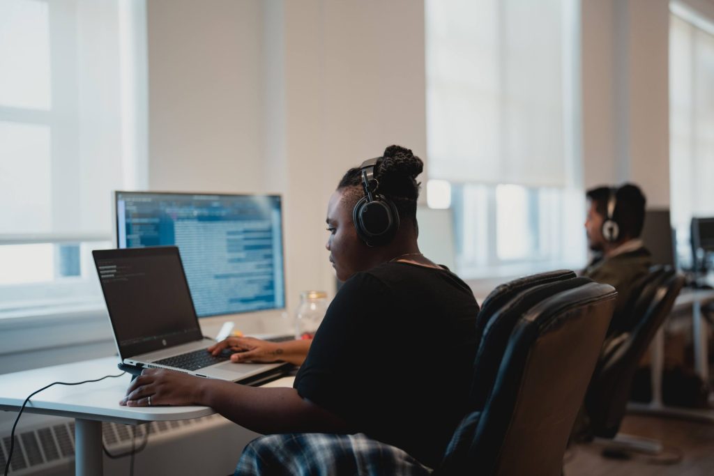 Four Eyes team members wearing headsets working at laptops in the open office