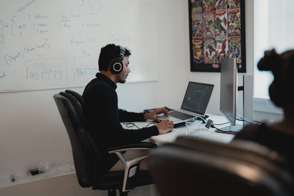 Four Eyes developer coding at his desk beside a whiteboard of system diagrams