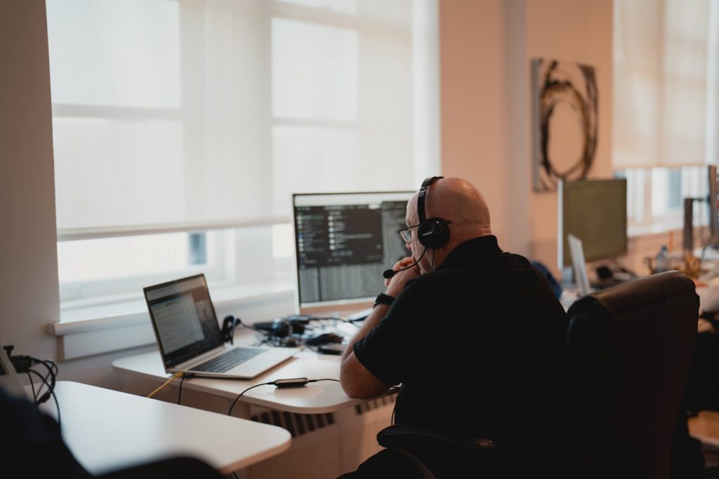 Four Eyes developer wearing a headset working across a laptop and monitor