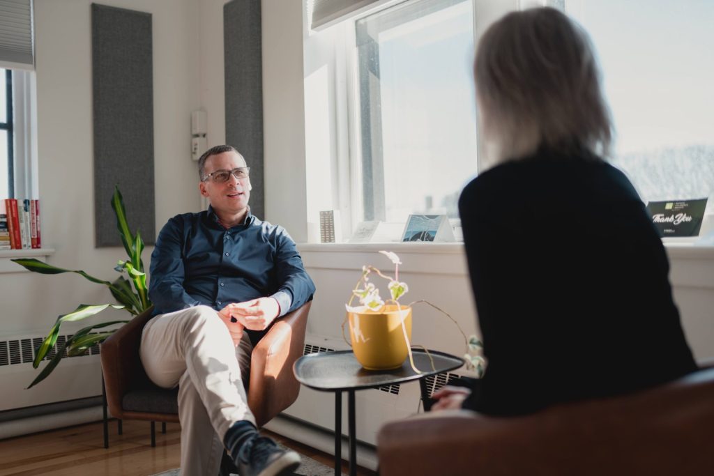 Two Four Eyes colleagues talking in armchairs by the office windows