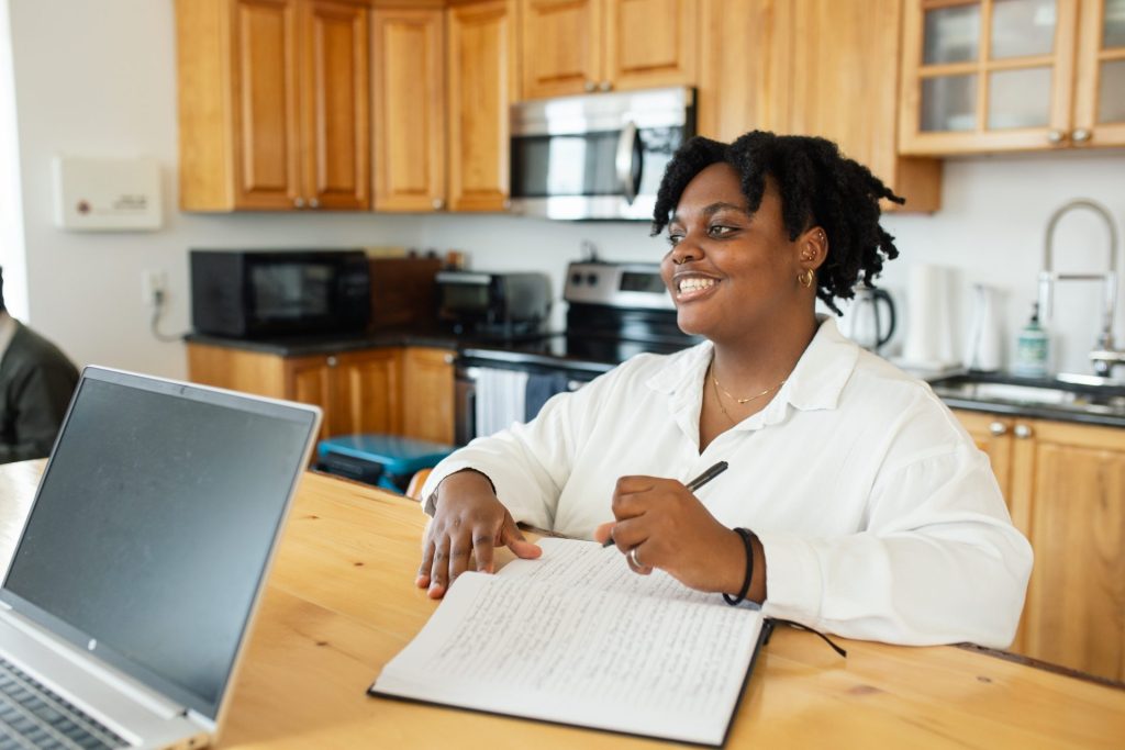 Four Eyes team member taking notes at a laptop in the office kitchen
