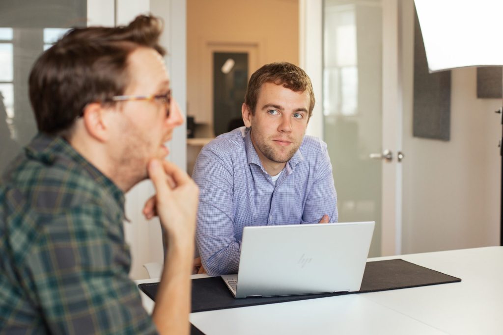 Two Four Eyes colleagues in conversation at a laptop