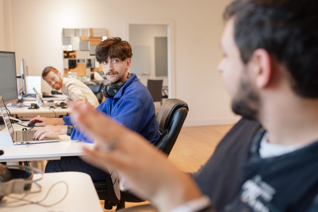 Four Eyes colleagues talking across desks in the open office