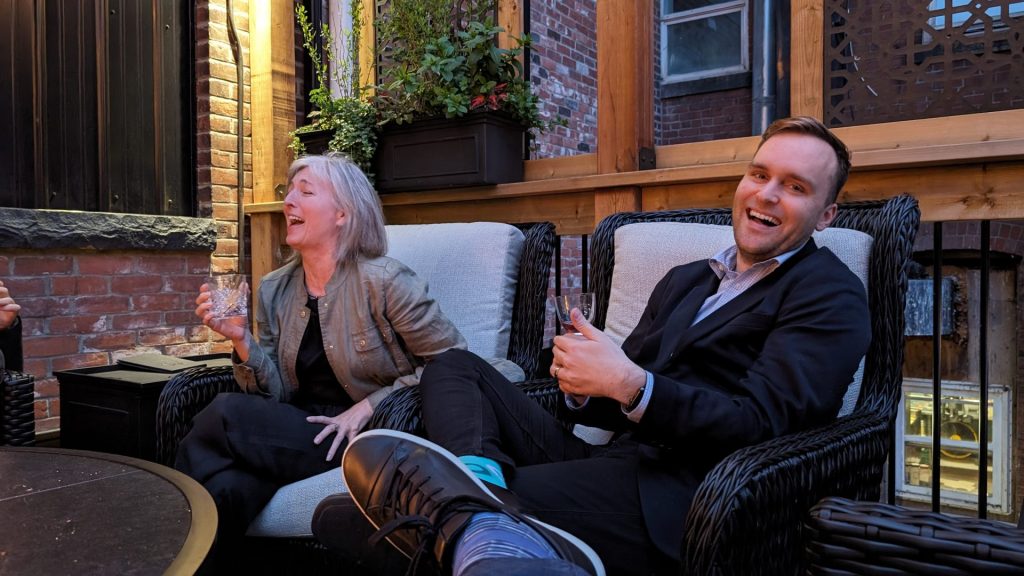 Two Four Eyes colleagues laughing on the office rooftop patio
