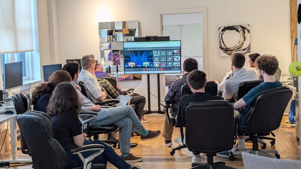 Four Eyes team gathered around a screen for a company meeting