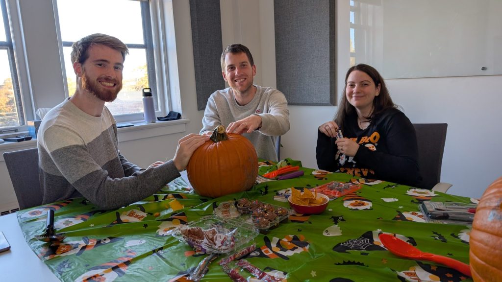 Four Eyes colleagues carving pumpkins at a Halloween office event